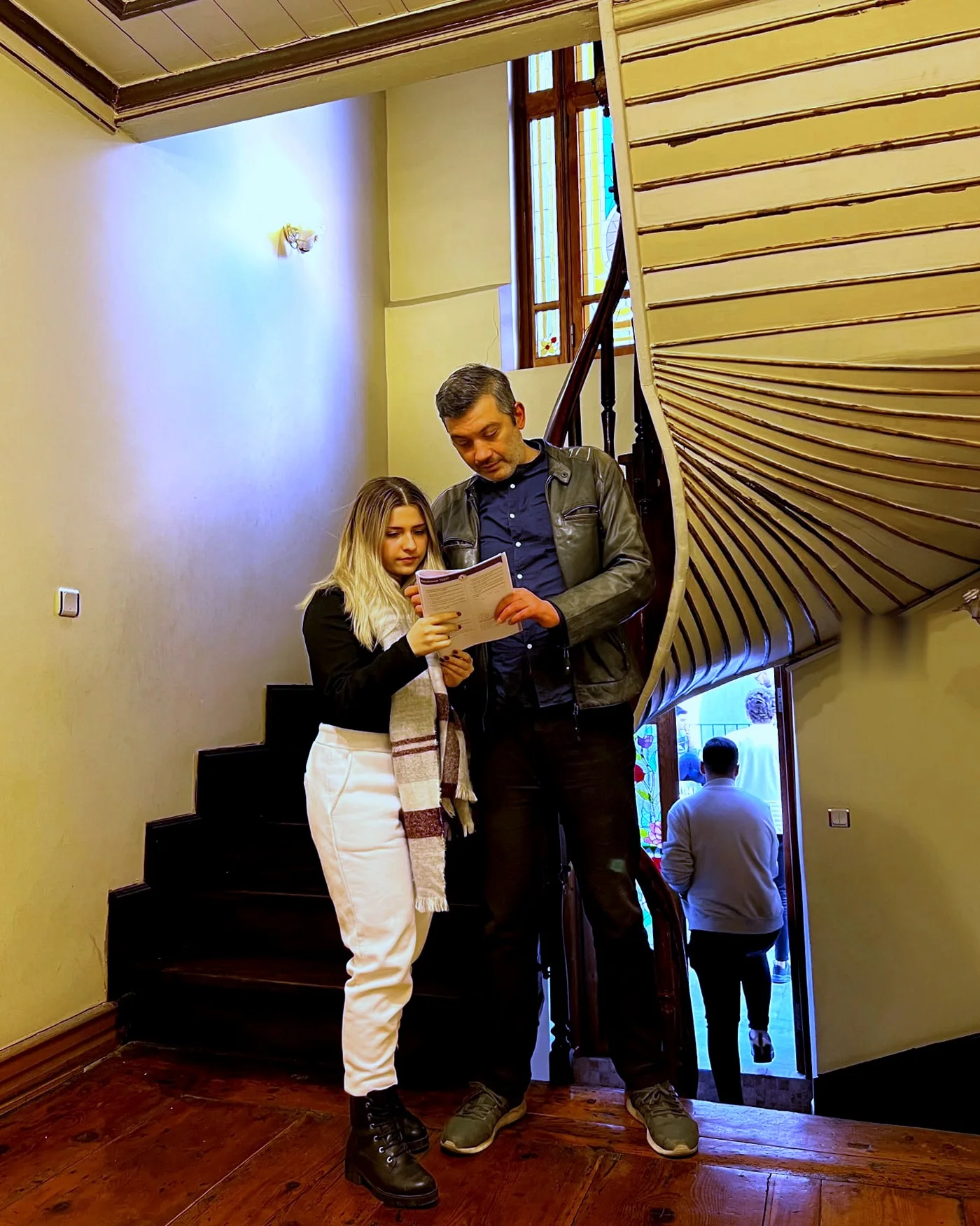Ozan Rona ve bir öğrenci, köşkün merdiveninde bir belge üzerinde
